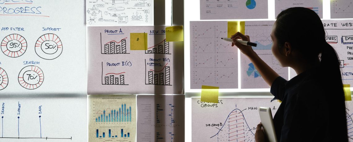 Business woman analyzing charts and graphs handing on the wall